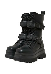 Czarne buty na platformie z błyszczącej skóry, z sznurowanym przodem, podwójnymi paskami z logo oraz ruggedowymi podeszwami.