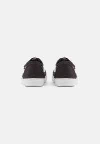 Sorte kanvas sneakers med hvite gummisåler, med lav-top design, rund tå og minimalistisk detaljer bak.