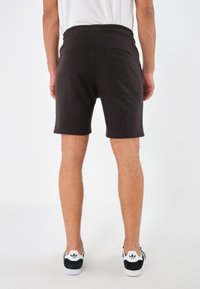 Shorts neri in cotone con vita a coste, tasche laterali e una tasca posteriore singola, caratterizzati da una texture liscia e una vestibilità rilassata.