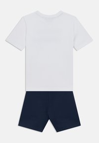 Λευκό βαμβακερό μπλουζάκι με κοντά μανίκια, σε συνδυασμό με σορτς από μπλε ναυτικό τζέρσεϊ. Απλός σχεδιασμός, χωρίς σχέδια ή αξιοσημείωτες λεπτομέρειες.