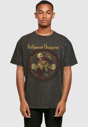 Svart oversized t-skjorte laget av bomull med grafisk trykk av skjeletter og teksten "Hollywood Vampires" i gull på forsiden.