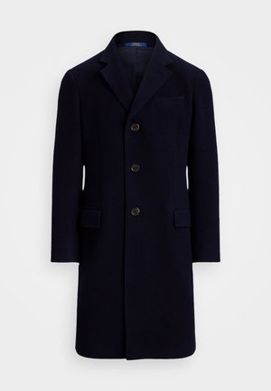 Cappotto di lana blu navy con colletto a revers, abbottonatura frontale a quattro bottoni e due tasche anteriori. Texture liscia e vestibilità sartoriale.
