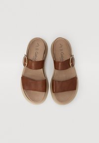 Brown leather slide sandals with two broad straps and a round gold buckle. Soft beige insole; curved, lightweight sole for comfort.