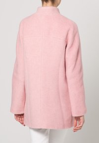 Abrigo de mezcla de lana rosa con cuello alto, silueta relajada, mangas largas y un acabado suave y texturizado. Espalda lisa con detalles mínimos.