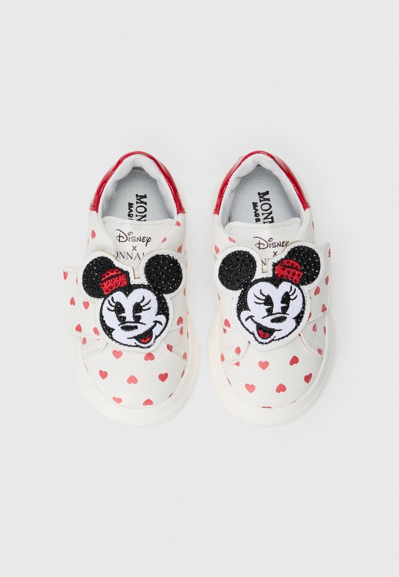 Chaussures blanches pour tout-petits avec des coeurs rouges et des patchs visage de Minnie Mouse portant des chapeaux rouges sur les brides, bordure rouge au talon.