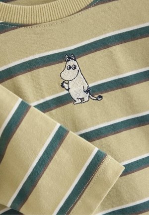 Stribet beige og grøn strikket stof med broderet tegneseriefigur, der ligner et lille, stående dyr med store øjne og hale.