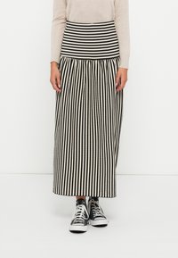 Svart og hvit stripete skjørt med en tettsittende strikket midje og rynket skjørt. Kombinert med svart og hvite joggesko.