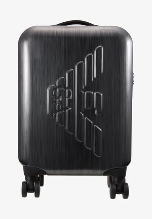 Mala preta de hard-shell com acabamento escovado, apresentando um design geométrico elevado e quatro rodas duráveis para fácil mobilidade.