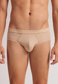 Beige Herren-Slip aus weichem Stoff, mit enger Passform, elastischem Bund und gefüttertem Frontbeutel mit verstärkten Nähten.