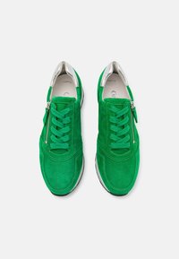 Green suede sneakers with perforated detailing, silver accents on the collar, and a side zipper. The laces are flat and green.