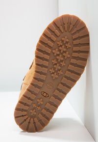 Sole in gomma marrone con motivo in rilievo, con logo ad albero e design non lasciato segni. Profondità ridotta con cuciture visibili.