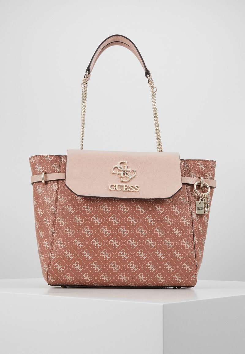 Borsa tote marrone con motivo, flap rosa chiaro, hardware dorato e manico a catena con il logo GUESS. Materiale testurizzato e forme distintive.