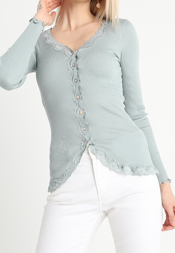 Cardigan a coste di colore azzurro chiaro con scollatura e orlo in pizzo ondulato, dotato di bottoni sulla parte anteriore e maniche lunghe.