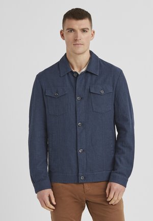Marineblaues, knöpfbares Jackett aus strukturiertem Stoff mit zwei Brusttaschen und klassischem Kragen. Braune Knopfdetails und Manschetten.