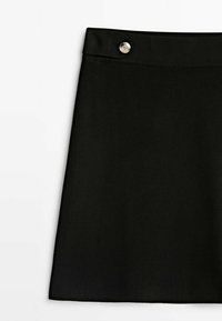 Jupe noire en forme de A faite en tissu lisse, présentant une taille avec un détail de bouton argenté à l'avant. Aucun motif supplémentaire n'est noté.
