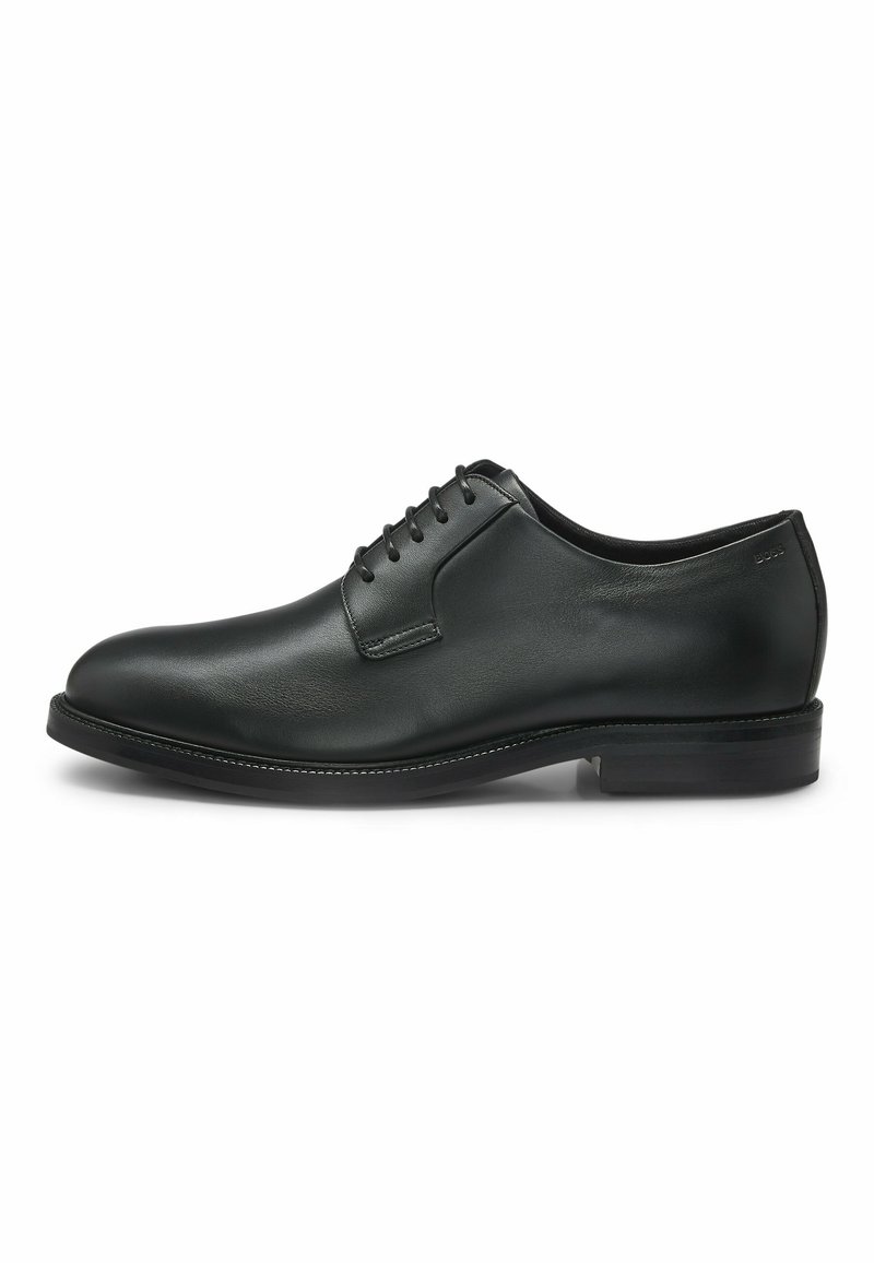 Scarpa da uomo in pelle nera con punta tonda, texture liscia, suola bassa, design con allacciatura a sei occhielli e dettagli di cucitura minimi.