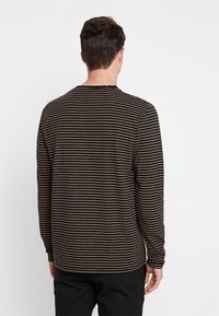 Langärmliges gestreiftes Hemd in Dunkelbraun mit hellbeigen horizontalen Streifen. Verfügt über einen Rundhalsausschnitt und einen lockeren Schnitt.