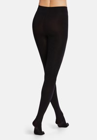 Leggings neri realizzati in un materiale liscio e elastico. Hanno una vita alta e una vestibilità aderente lungo la gamba, con i piedi nudi visibili.