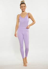 Completo da ginnastica di colore viola chiaro composto da un top aderente con spalline sottili e leggings a vita alta, entrambi realizzati in un tessuto liscio e elastico.