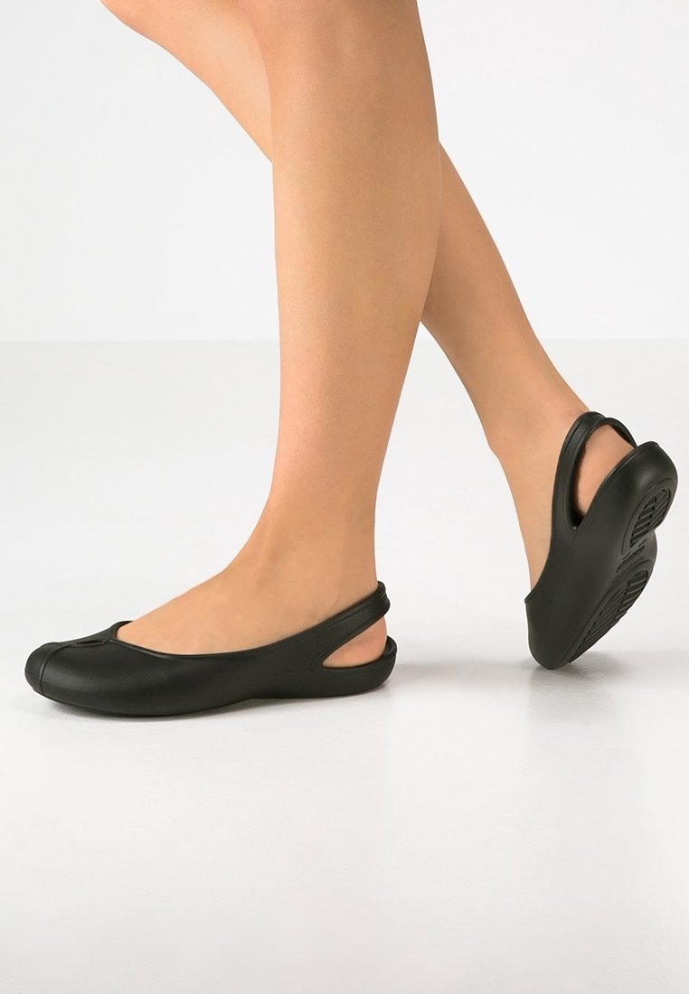 Bottines noires à enfiler avec un bout arrondi, un talon ouvert et un soutien de la voûte plantaire. Fabriquées en matériau lisse ressemblant à du caoutchouc avec une semelle texturée.