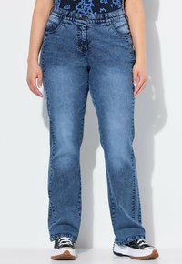 Pantalones de mezclilla azul con corte recto, cinco bolsillos y cierre clásico de botón. Presentan un lavado desvaído y sutiles variaciones en la textura.