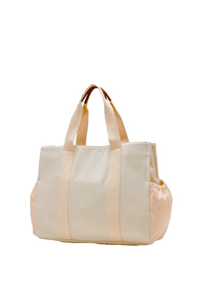 Borsa a spalla in canvas beige con accenti di rosa pallido. Presenta un tessuto resistente, doppi manici e un fondo arrotondato con un lato arricciato.