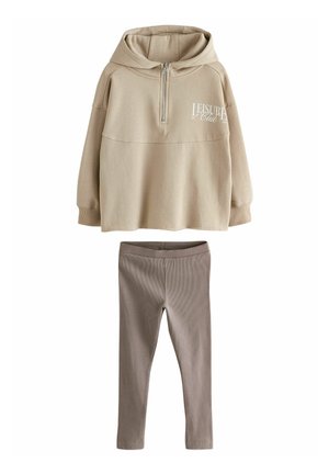 Felpa beige con colletto zip e scritta frontale abbinata a leggings marroni a coste. Materiale in cotone morbido, vestibilità comoda e design minimal.