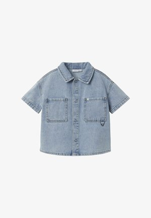 Camisa de mezclilla de manga corta en azul claro, con cuello puntiagudo, dos bolsillos frontales y cierre de botones en la parte delantera con costuras en contraste.