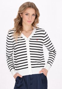 Cardigan cu dungi alb-negru, cu decolteu în V, închidere cu butoane și un mic detaliu sub formă de ancoră roșie pe partea stângă. Material moale, tricotat.