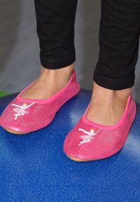 Roze glinsterende balletschoenen met een stoffen bovenkant, voorzien van een geborduurd ballerina-ontwerp en een zachte zool, gedragen op een blauwe ondergrond.