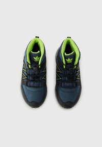 Des chaussures de randonnée bleu foncé avec des accents noirs, une doublure verte et des lacets réfléchissants jaunes. Matériaux en maille et synthétiques avec des surfaces texturées.