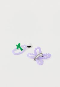 Paarse kralen accessoires: één in de vorm van een vlinder met een metalen accent, een ander in de vorm van een lus met een groene strik en witte details.