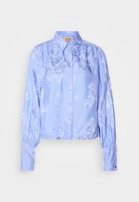 Blouse bleu clair à manches longues boutonnée, avec motif jacquard floral, col pointu, poignets froncés et coupe légèrement courte.