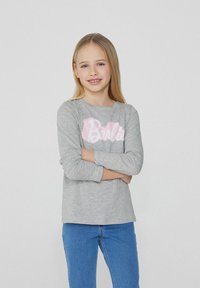 Šedé tričko s dlouhým rukávem a růžovým logem "Barbie" na hrudi, doplněné modrými džíny. Měkká látka s volným střihem.