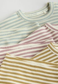 Three ribbed T-shirts in blue, pink, and yellow-green stripes with cream accents; round necks and soft texture.
