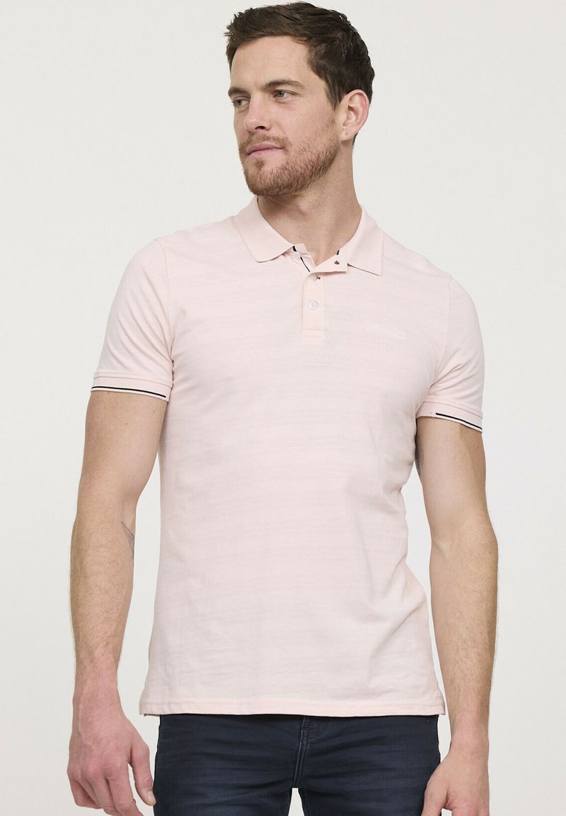 Polo shirt rose clair avec un col, patte de boutonnage à deux boutons et accents noirs sur les ourlets des manches. Fabriqué en tissu doux avec une texture subtile.
