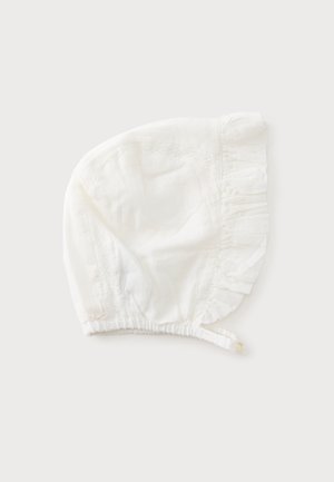 Hvid babyhue med flæsekant og knaplukket hagesmæk, lavet af blødt stof med subtile blonderdetaljer.