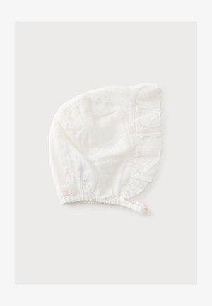 Hvid babyhue med flæsekant og knaplukket hagesmæk, lavet af blødt stof med subtile blonderdetaljer.