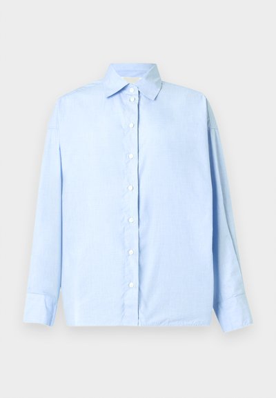 Ανοιχτό μπλε πουκάμισο με μακριά μανίκια, κουμπωτό μπροστά με γιακά μυτερό και μανσέτες με ένα κουμπί, απλωμένο επίπεδα πάνω σε λευκό φόντο.