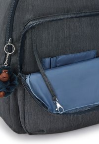 Zaino in denim nero con finitura testurizzata, dotato di uno scomparto interno blu, chiusura a zip e un portachiavi a forma di scimmia pelosa attaccato.