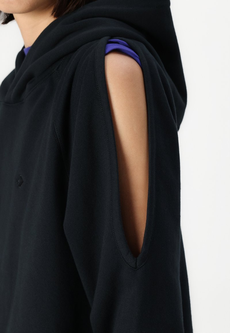 Felpa nera con cappuccio e dettagli con spalla scoperta, realizzata in tessuto morbido. Presenta un logo discreto e un design dalla vestibilità rilassata.