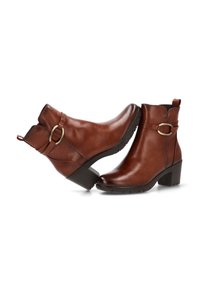 Botines de cuero marrón con un tacón bajo en bloque, punta redondeada y un detalle de hebilla en el lateral. Textura suave y una lengüeta en la parte trasera.