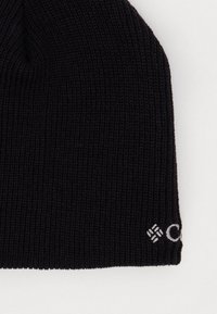 Berretto a maglia nera con texture a coste. Presenta un piccolo logo ricamato in bianco sul bordo inferiore. Il design è aderente e fitted.