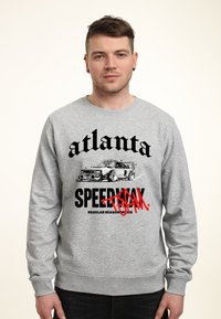 Šedá mikina se grafickým potiskem auta a textem v tučných černých a červených písmenech, včetně "Atlanta" a "Speedway".