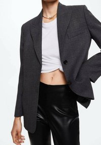 Gray tailored blazer with a notch lapel, single button closure, and pocket; paired with a white cropped t-shirt and black leather pants.