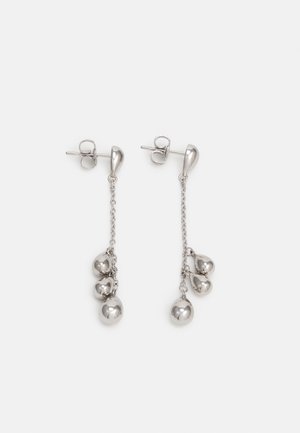 Srebrne wiszące kolczyki z trzema małymi zawieszkami w kształcie serc i jedną okrągłą zawieszką na cienkich łańcuszkach.