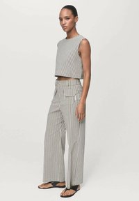 Gestreiftes Cropped-Top und weit geschnittene Hose in Beige und Weiß. Die Hose hat Taschen, und beide Kleidungsstücke verfügen über eine weiche Textur und einen lässigen Schnitt.