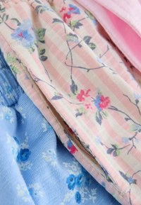 Morbido tessuto con motivi floreali in tonalità pastello rosa e blu, caratterizzato da strisce rosa e delicati fogliame verde su una trama piegata.