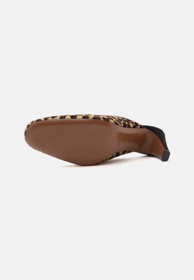 Chaussure à talon haut imprimée léopard, couchée sur le côté, montrant une semelle marron lisse et un talon noir fin.