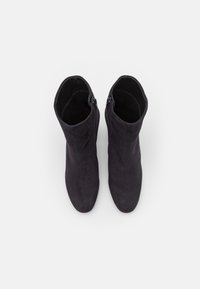 Stivaletti neri in suede con una texture liscia, punta affusolata e zip laterali, caratterizzati da un design elegante e da accentuazioni minime.